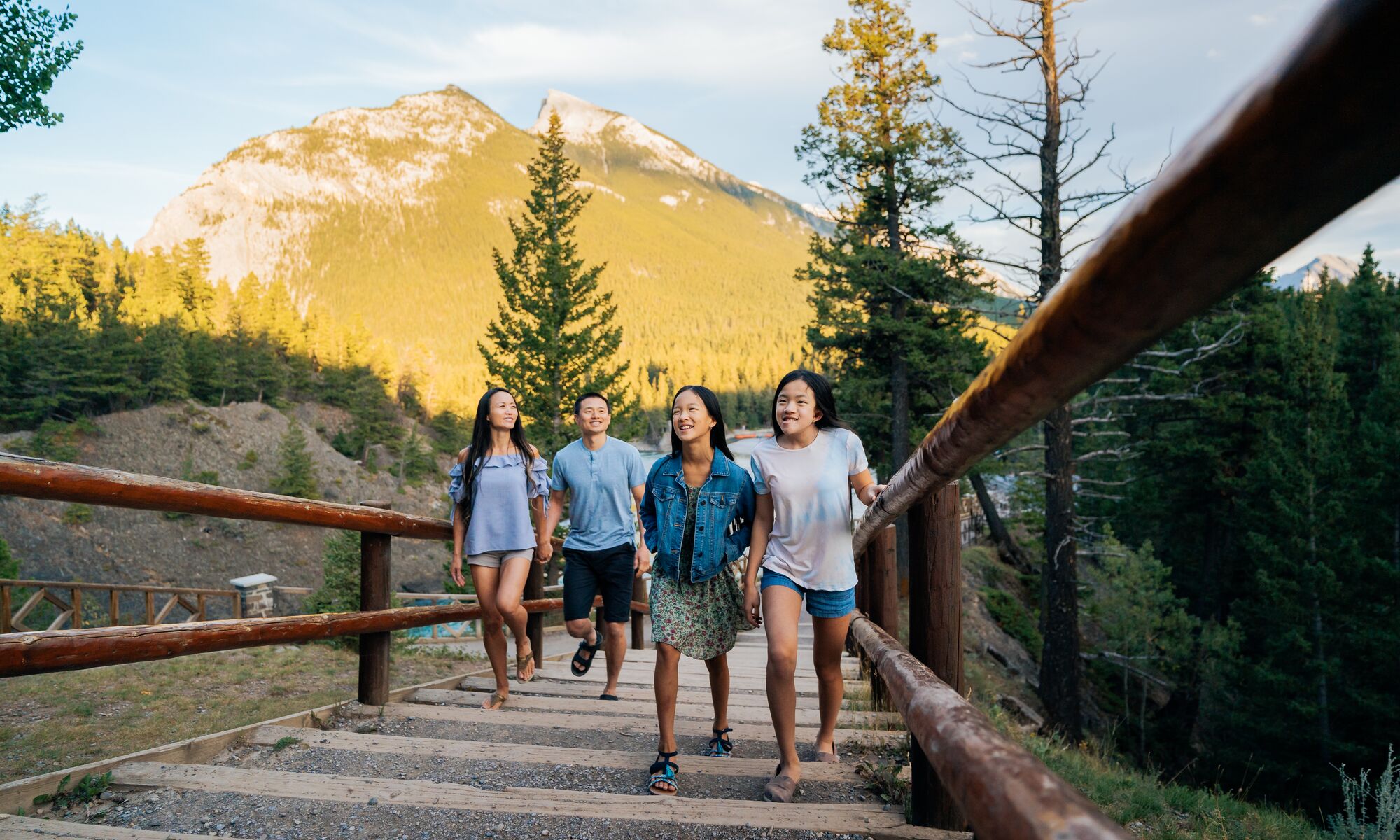 A family of four walking along the Bow River, a popular thing to do in Banff National Park