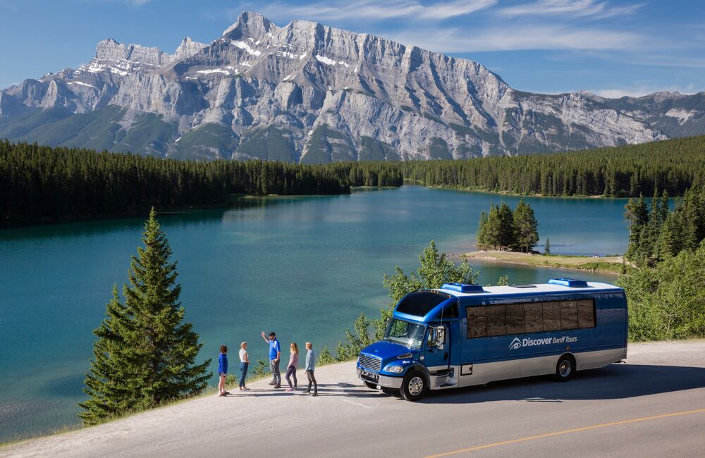 A tour bus driving the Icefields parkway with Bow Lake in the background.
