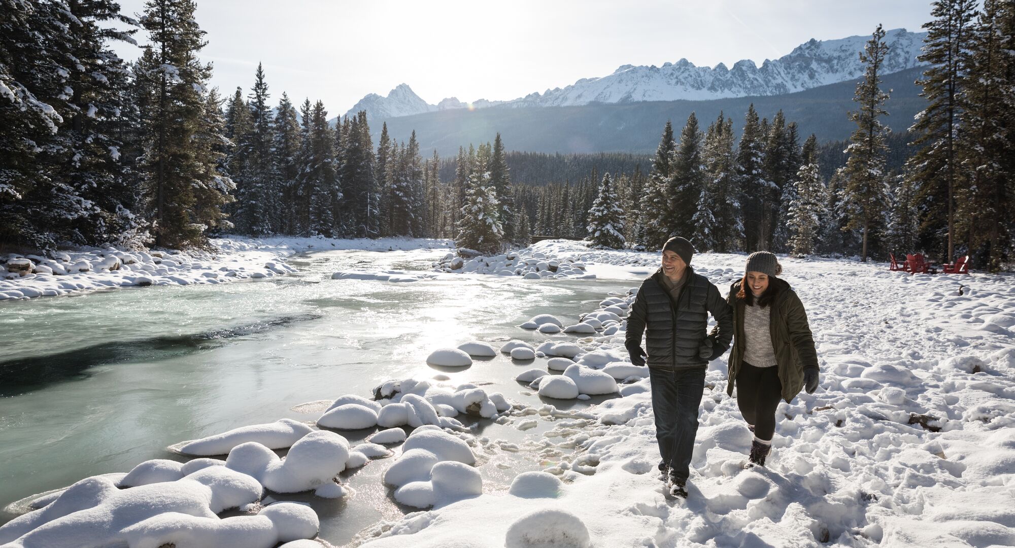 A couple walking along the Bow river in spring with snow in Banff National Park