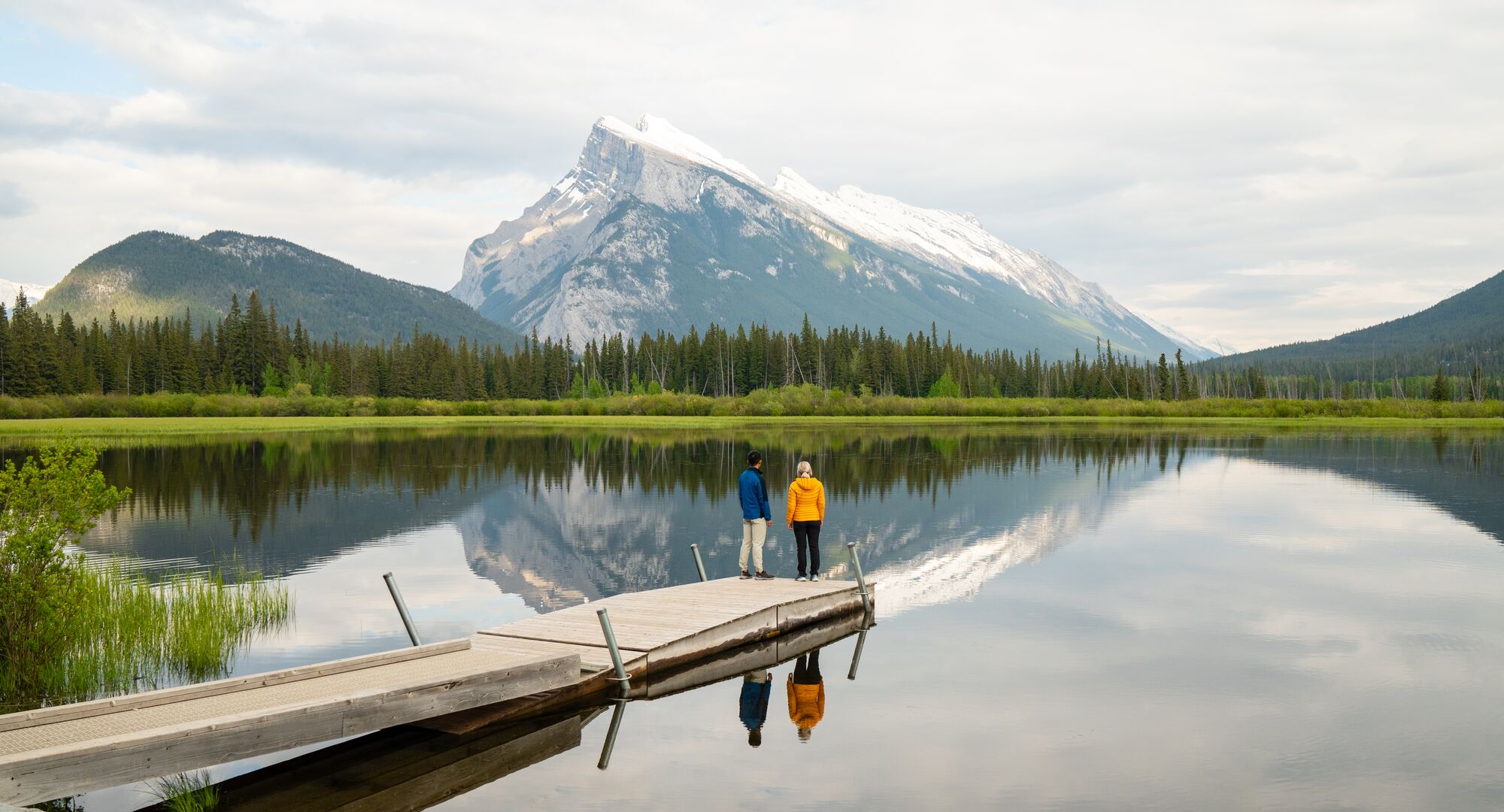 Two people on the dock at Vermilion Lakes for sunrise in the summer