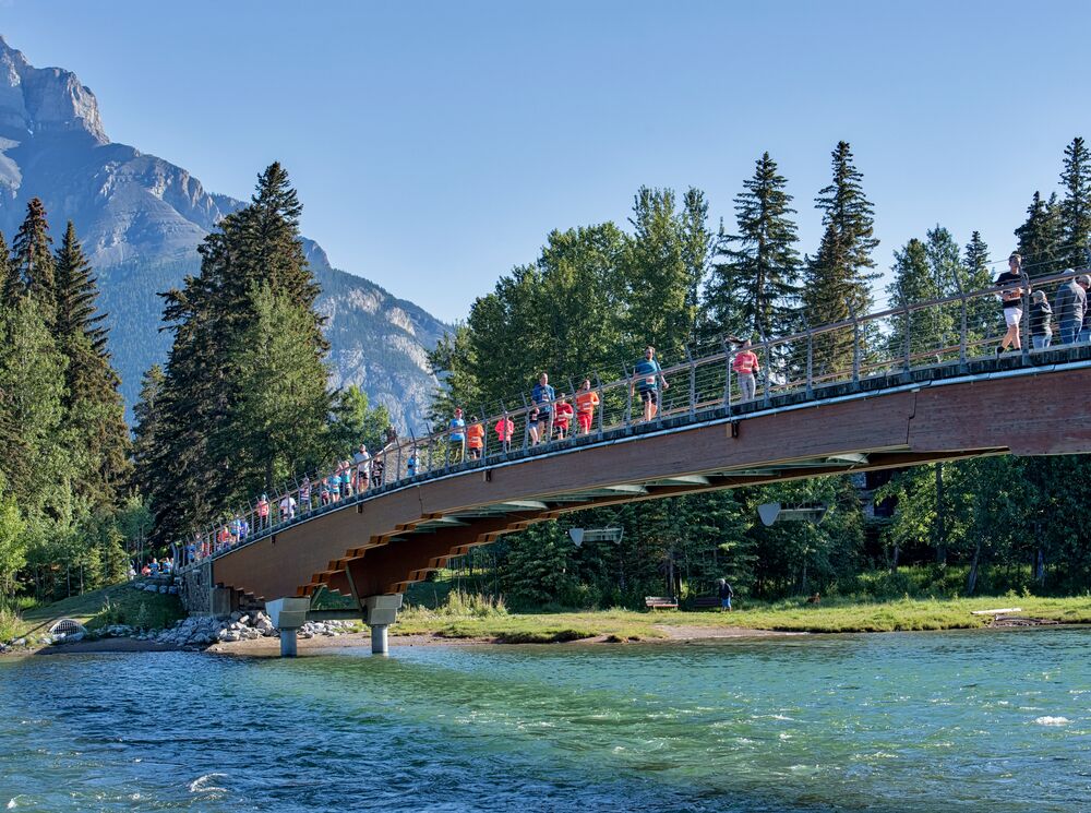 People running across the Banff Pedestrian Bridge during the annual Melissa's Road Race