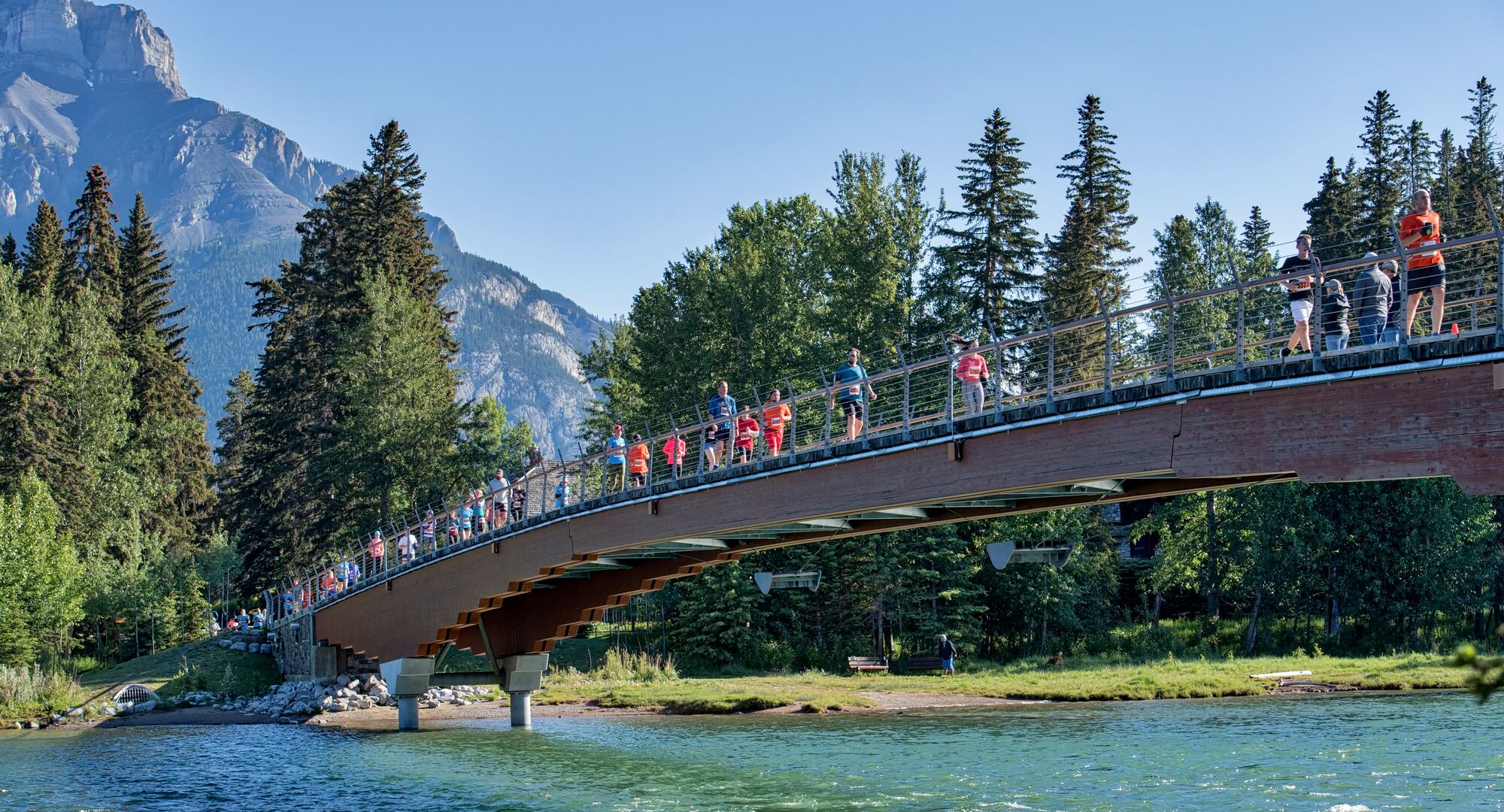 People running across the Banff Pedestrian Bridge during the annual Melissa's Road Race