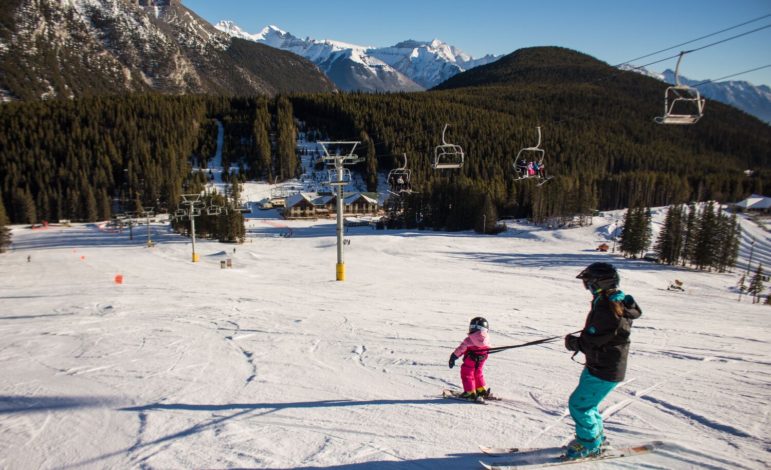 A parent and their kid go down the Cascade run at Mt. Norquay Ski Resort in Banff National Park.