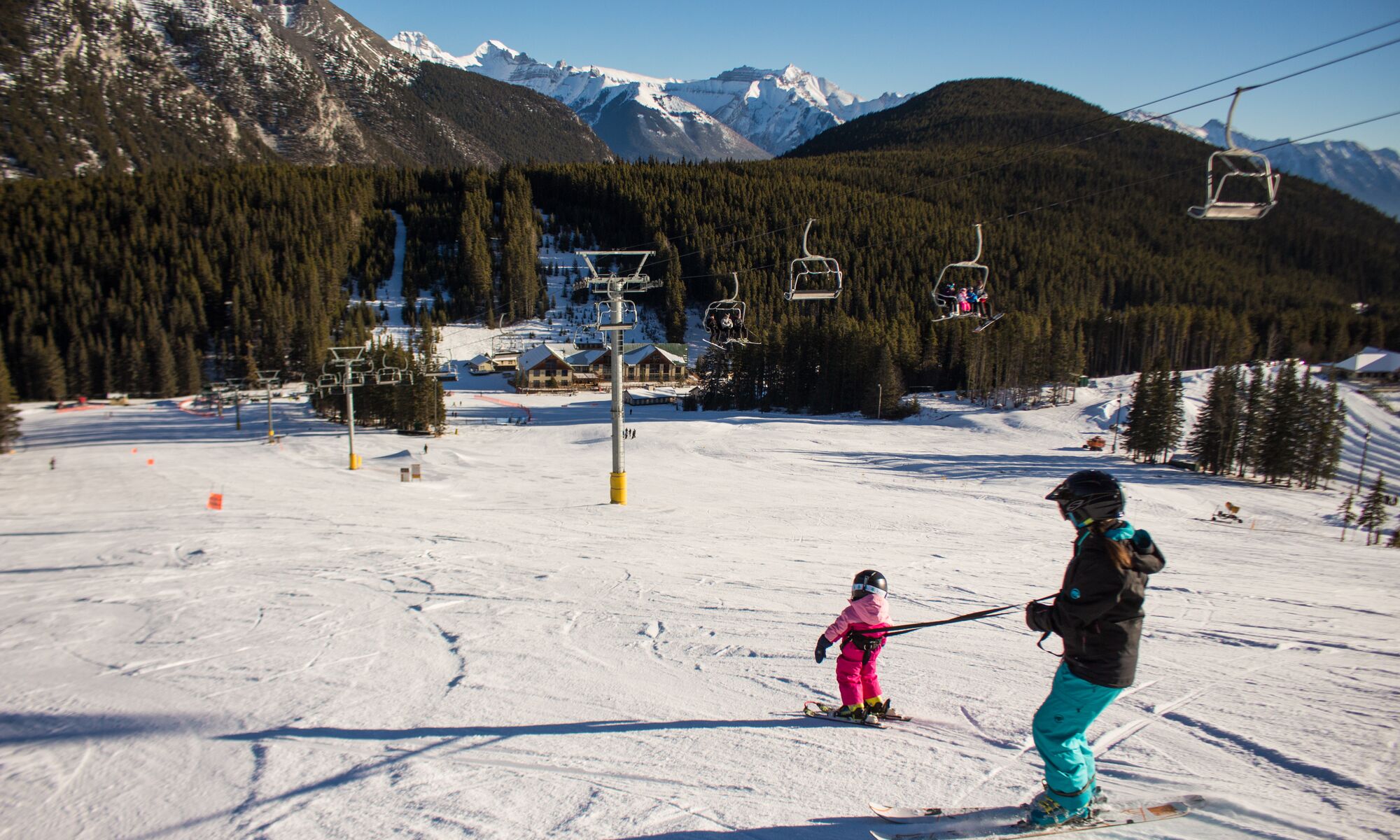 A parent and their kid go down the Cascade run at Mt. Norquay Ski Resort in Banff National Park.