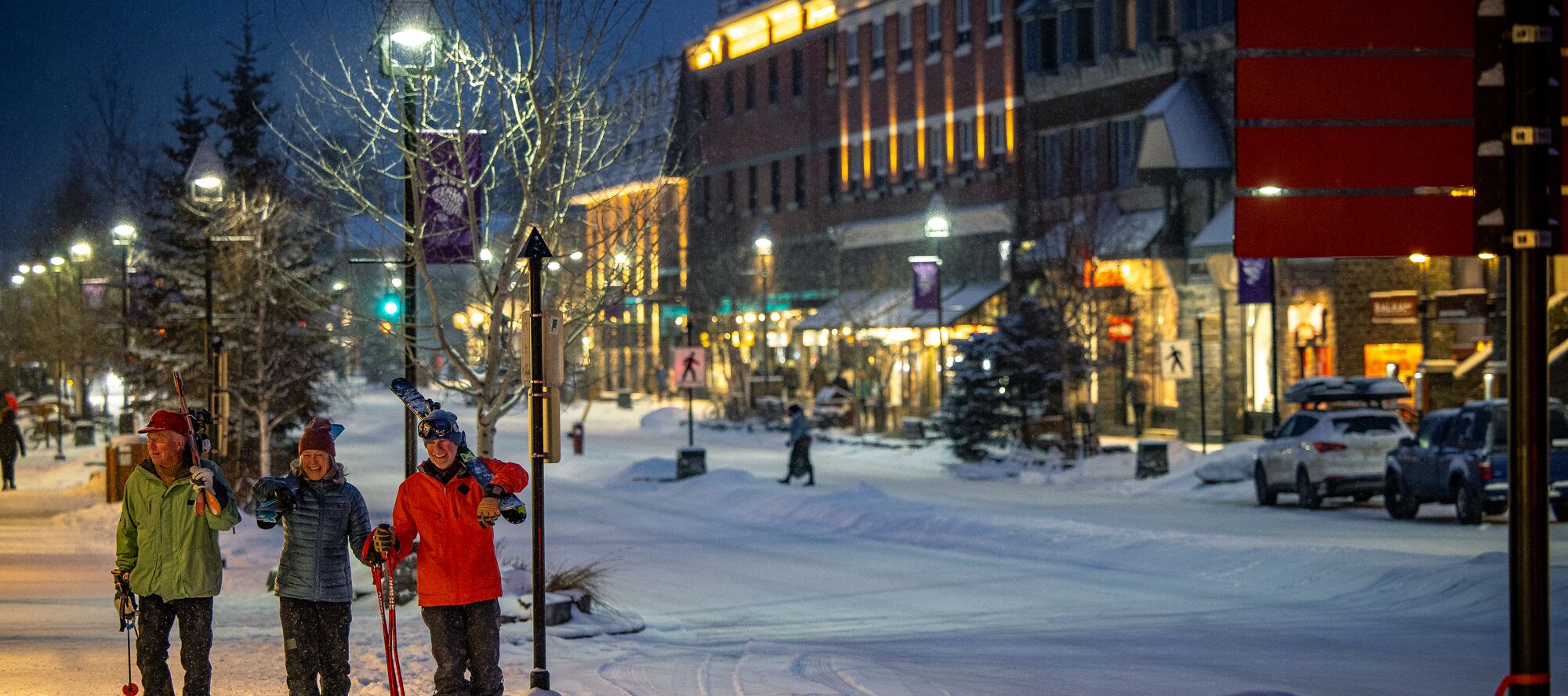 Skiers walk down Banff Avenue on a snowy evening in Banff National Park
