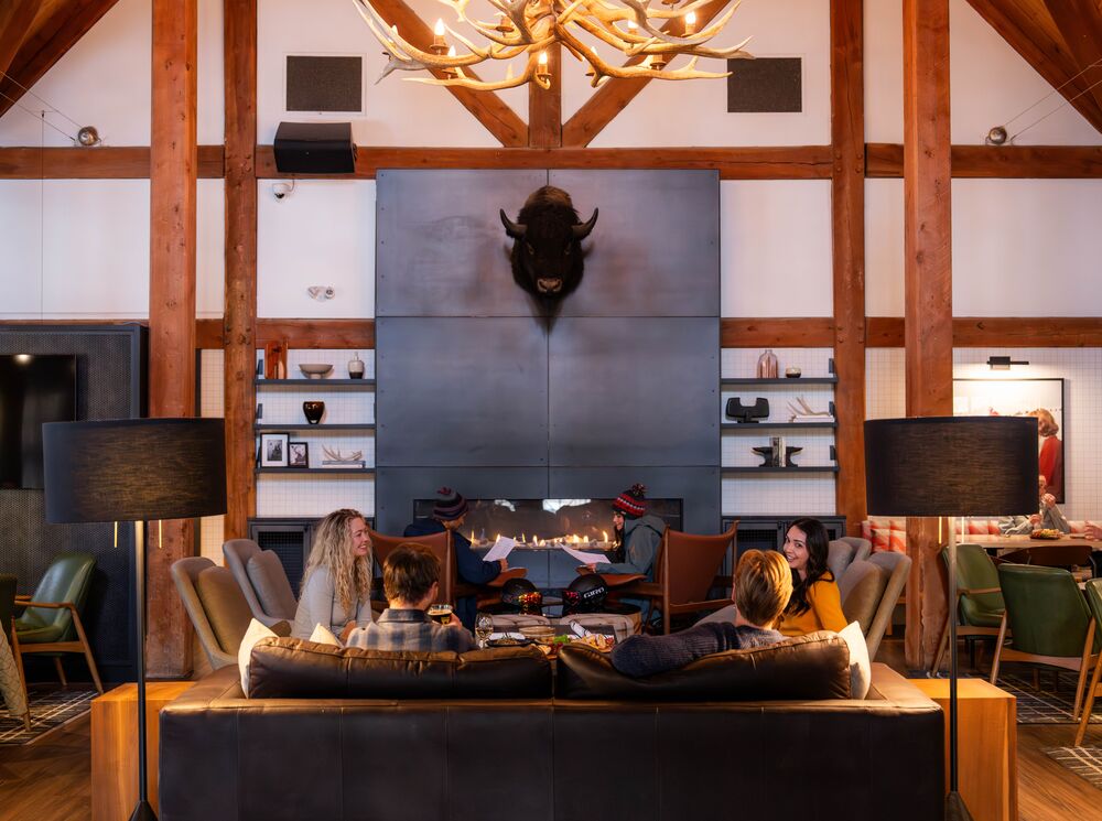 Interior image of the Prow featuring a fireplace and people sitting around tables at the restaurant in Banff, Canada.