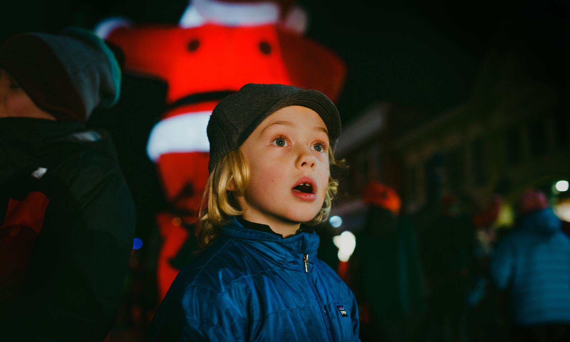 A kid looks on in awe with a giant inflatable Santa Claus behind him in Banff National Park.