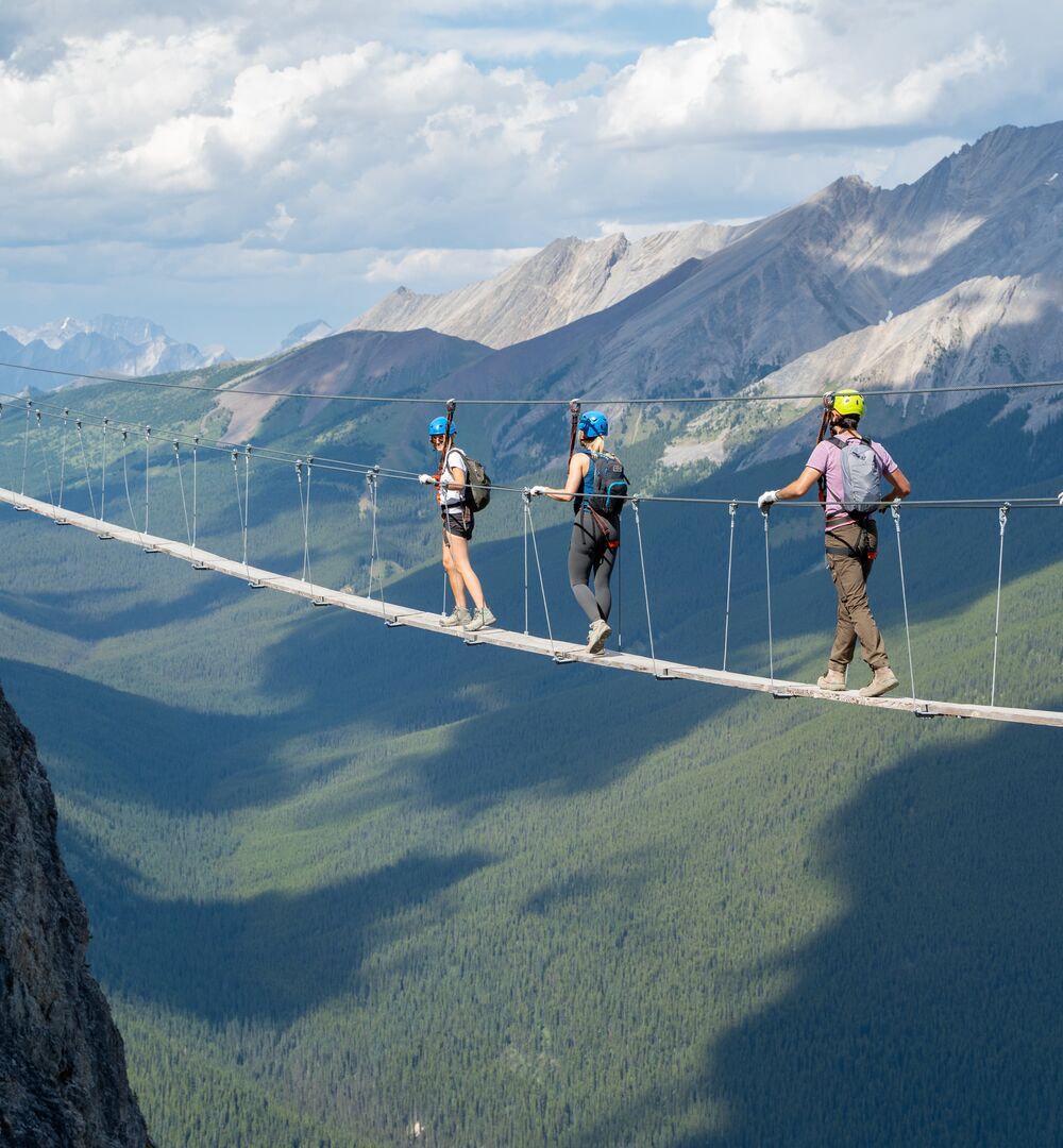 A group of people crossing a wooden suspension bridge at the Mt. Norquay Via Ferrata