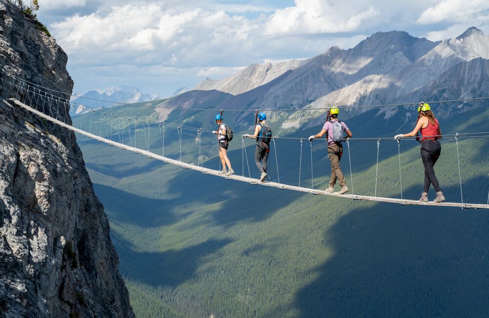 Four people walking across a bridge on the Via Ferrata at Mount Norquay in Banff National Park
