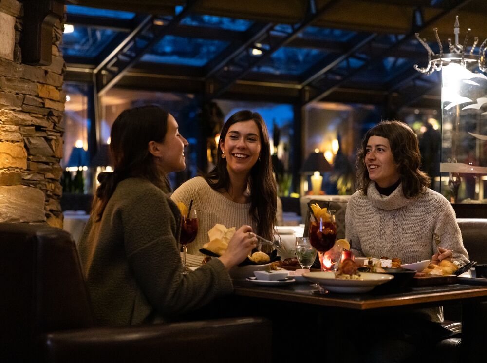 Three friends enjoy dinner at La Terrazza at Banff Park Lodge in Banff National Park.