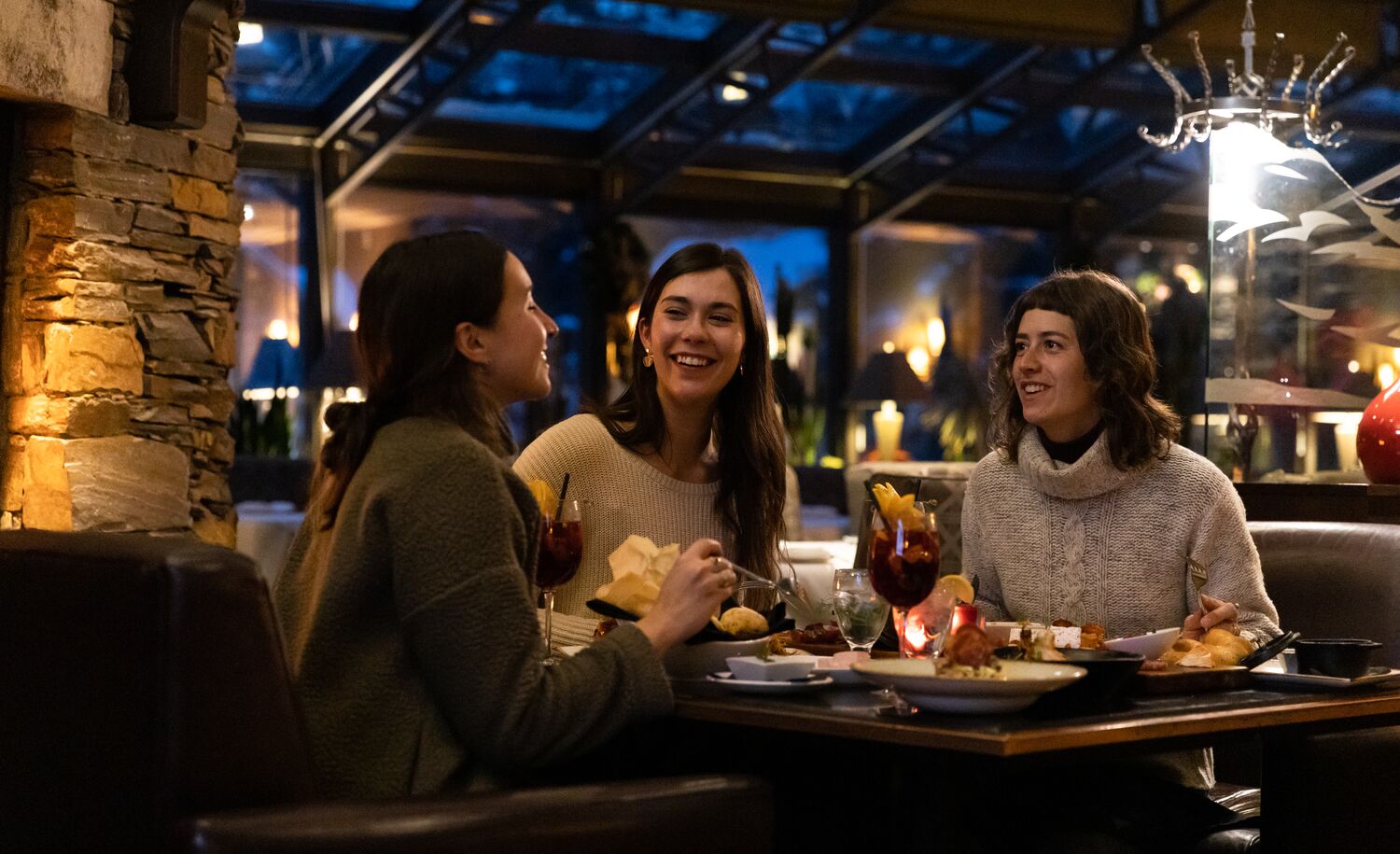 Three friends enjoy dinner at La Terrazza at Banff Park Lodge in Banff National Park.