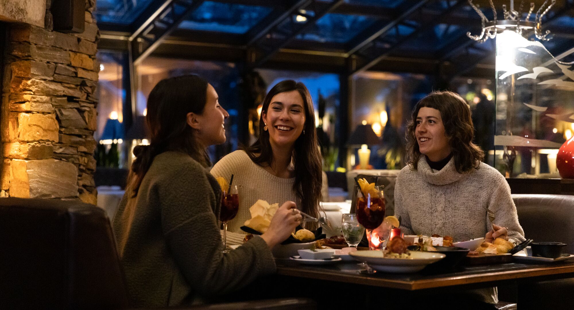 Three friends enjoy dinner at La Terrazza at Banff Park Lodge in Banff National Park.