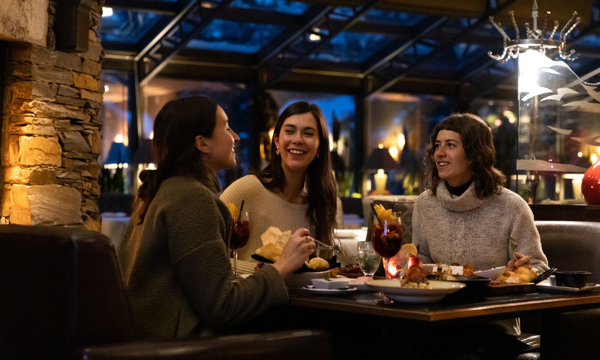 Three friends enjoy dinner at La Terrazza at Banff Park Lodge in Banff National Park.