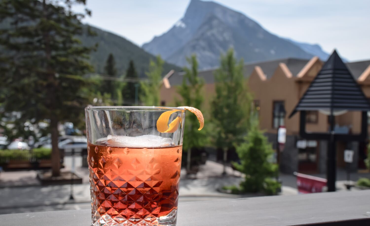 A drink sits on the patio railing with a view of Mount Rundle at PARK Distillery in Banff National Park.
