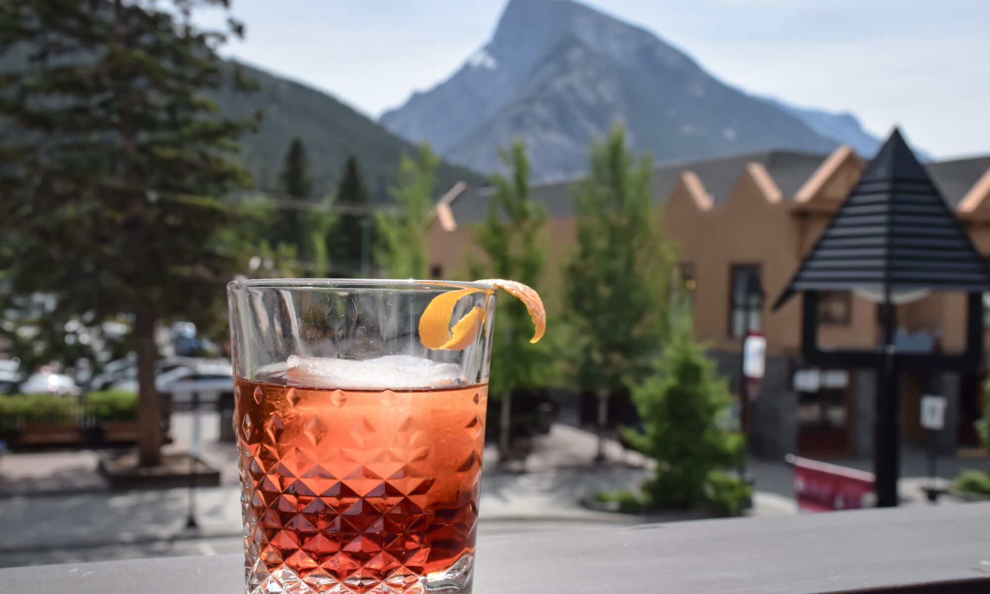 A drink sits on the patio railing with a view of Mount Rundle at PARK Distillery in Banff National Park.