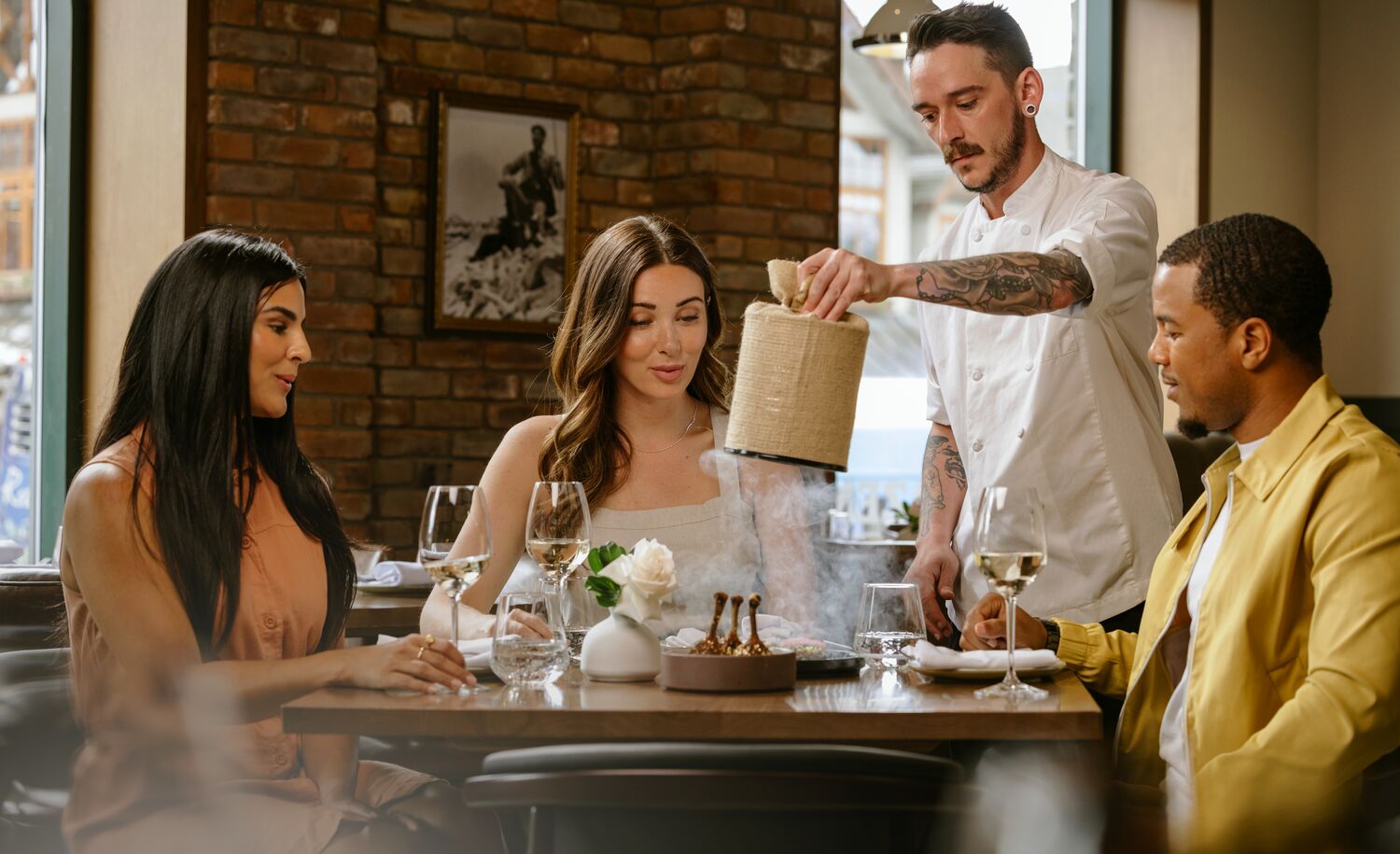 A waiter pulls the cover off a dish as three people look on in awe at Brazen in the Mount Royal Hotel in Banff.