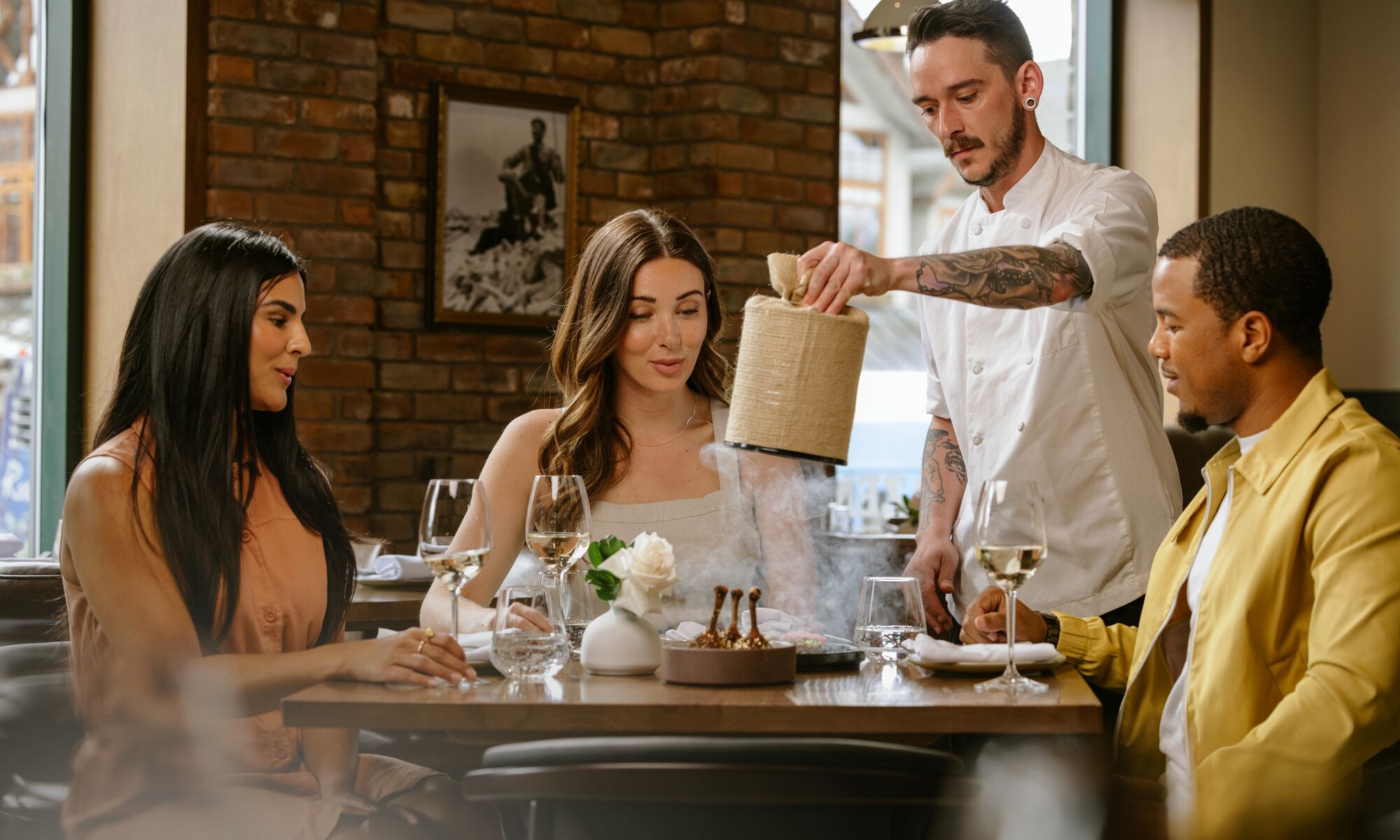A waiter pulls the cover off a dish as three people look on in awe at Brazen in the Mount Royal Hotel in Banff.