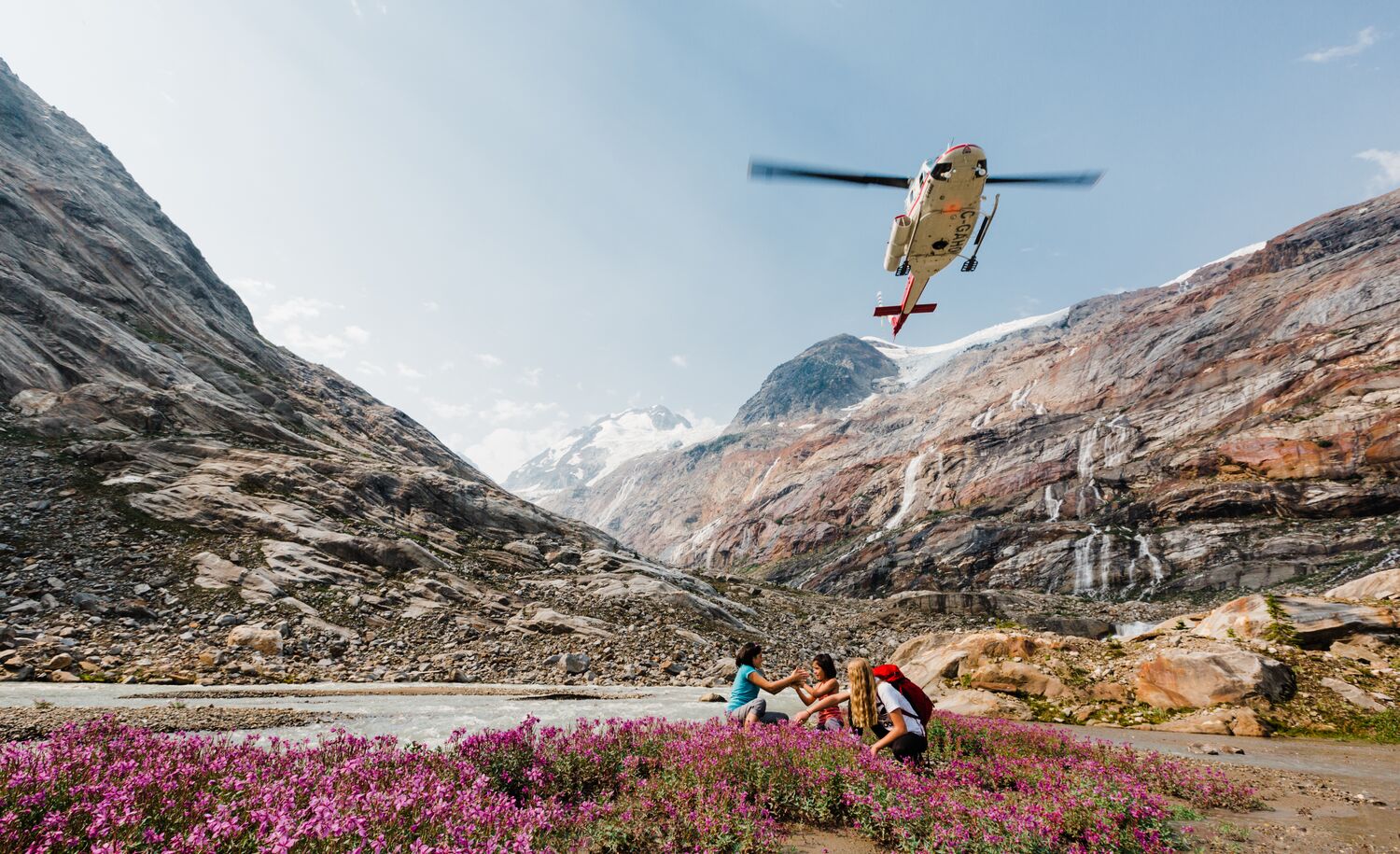 A helicopter flies over a group on a heli-hiking adventure with CMH in Banff National Park