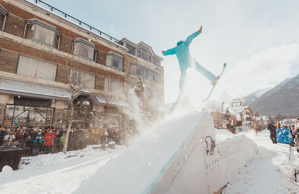 A horse pulls a trick skier over a snow jump in a Skijoring event on Banff Ave in Banff, Canada.