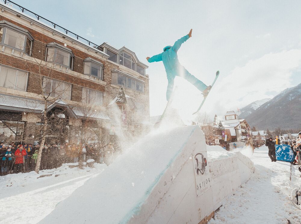 A horse pulls a trick skier over a snow jump in a Skijoring event on Banff Ave in Banff, Canada.