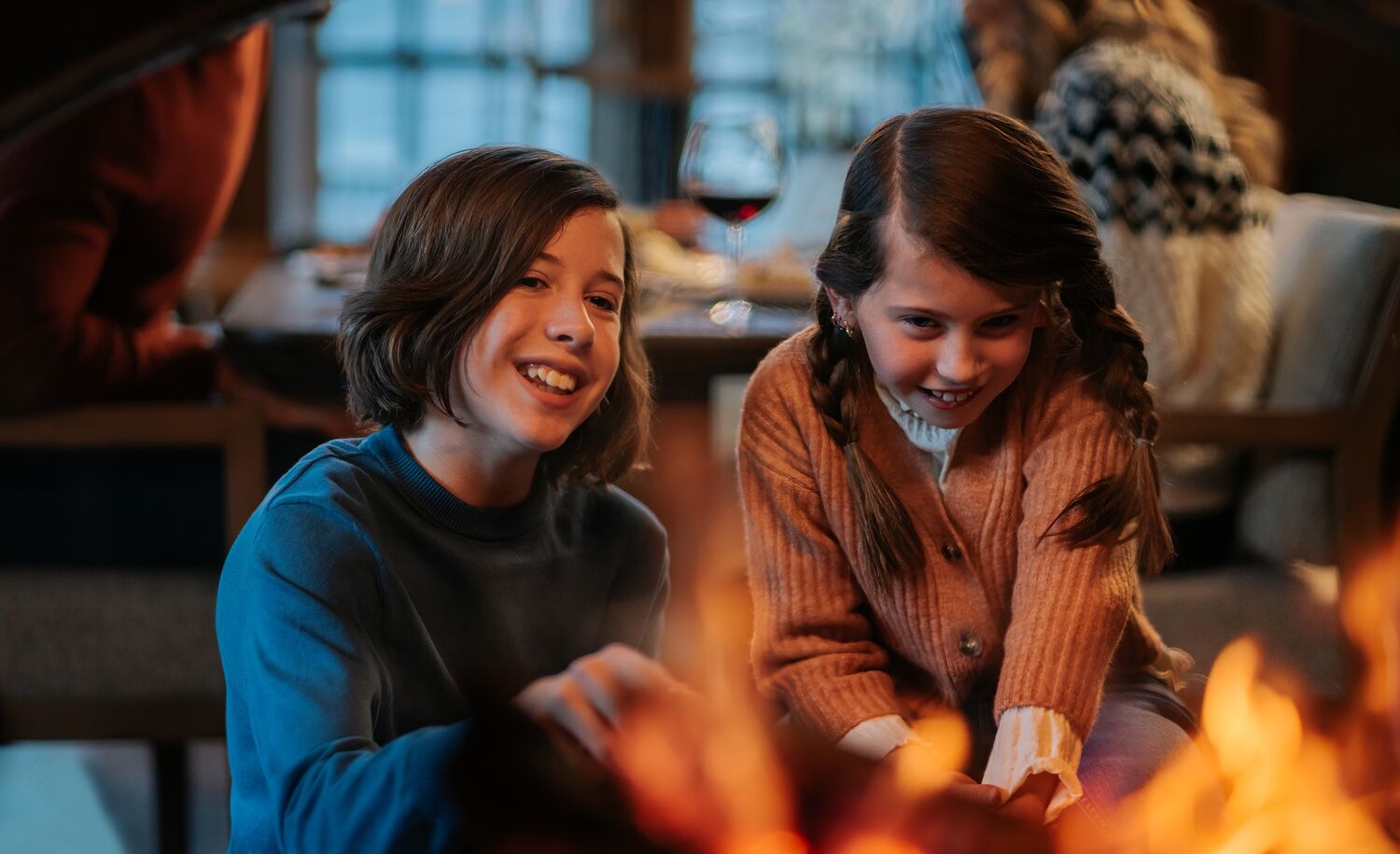 Two kids sit in front of a fireplace at Bluebird Steakhouse in Banff.