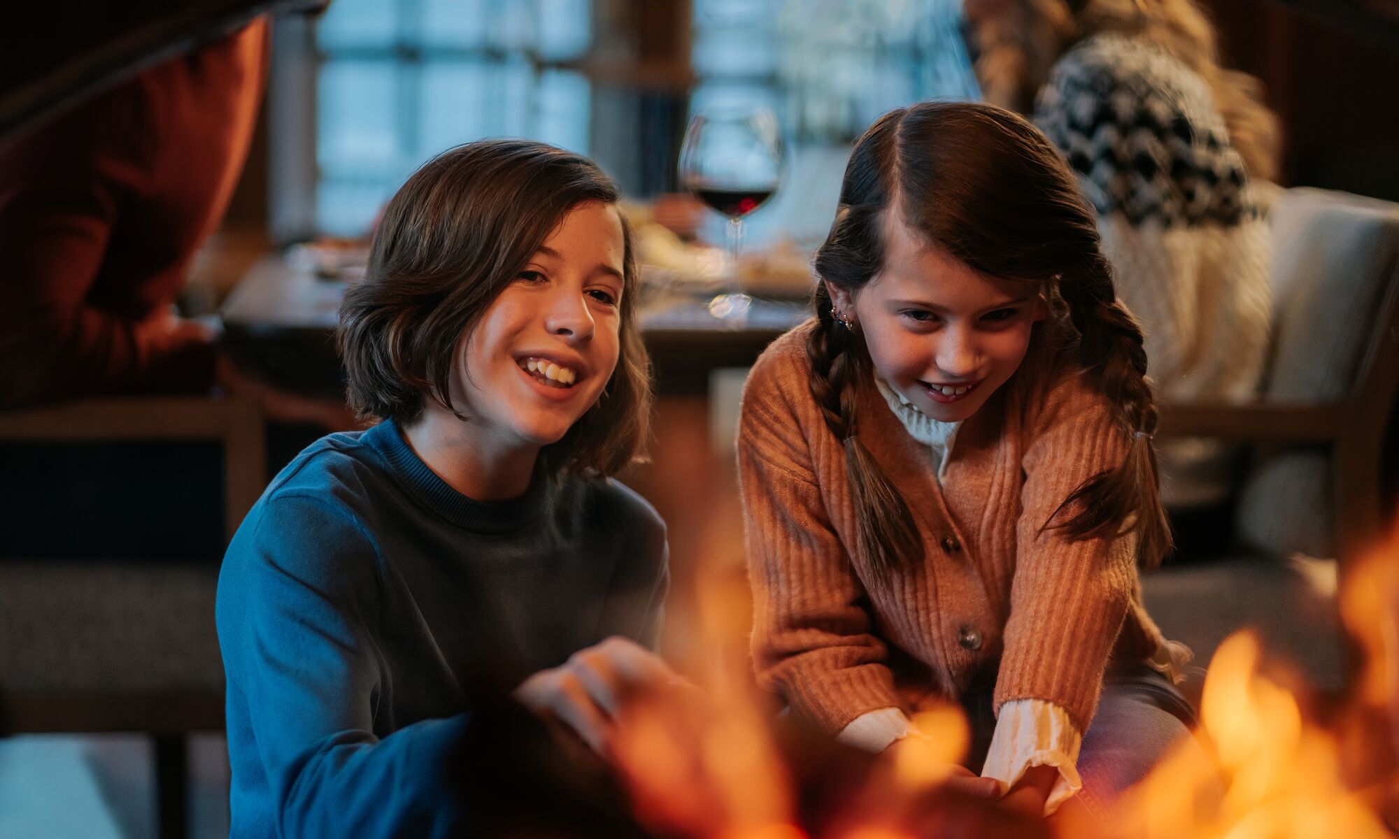 Two kids sit in front of a fireplace at Bluebird Steakhouse in Banff.