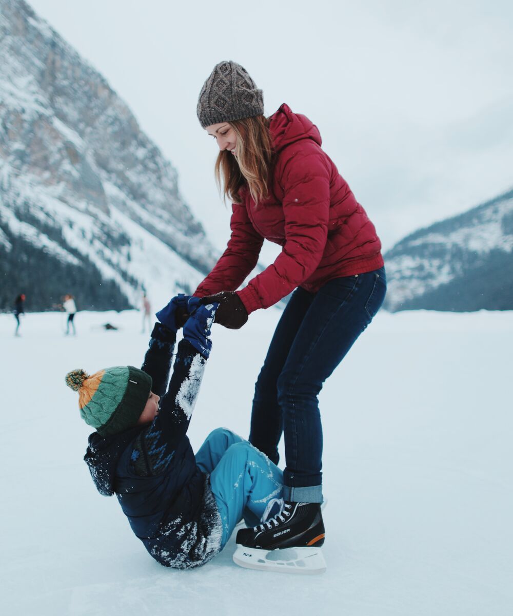 A mum and son are playing on the ice at Lake Louise during the winter in Banff National Park