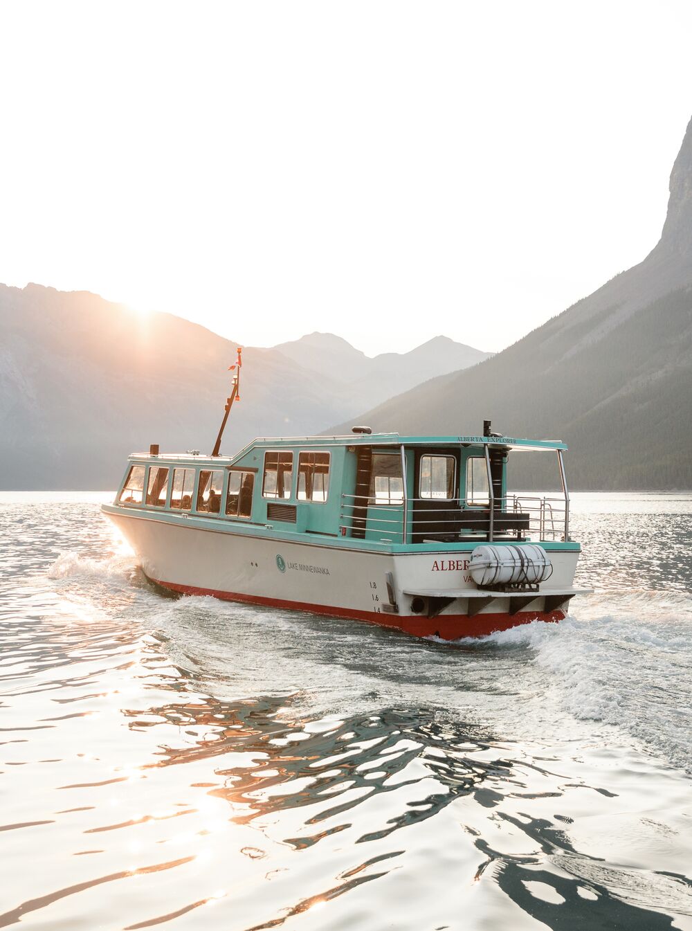 A boat cruise on Lake Minnewanka at sunset with mountains in the background