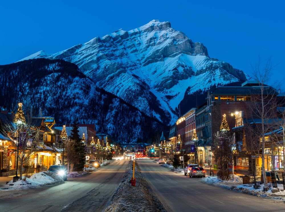 Cascade Mountain rises above Banff Avenue, which features many Banff restaurants, in the winter at blue hour in  Banff, Canada.
