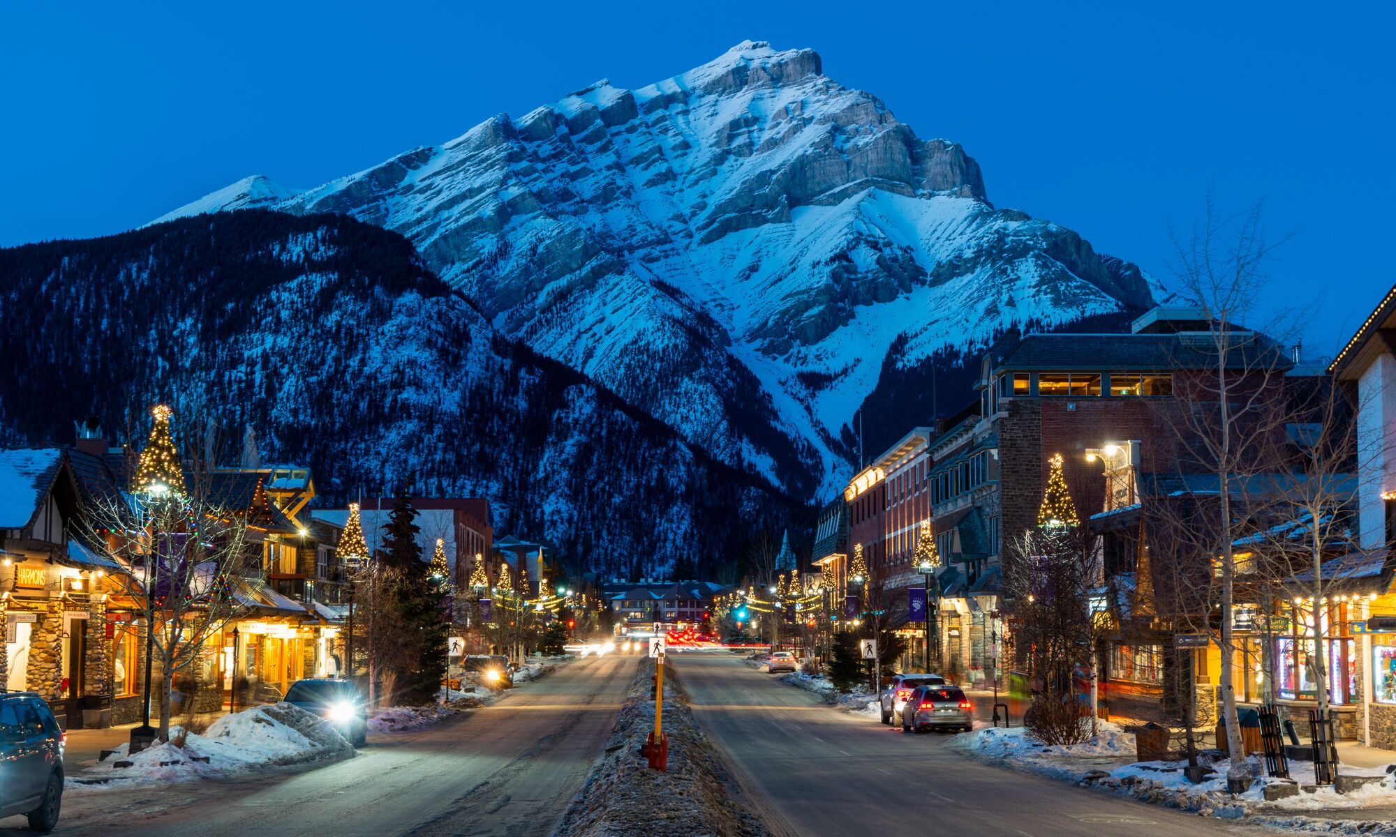 Cascade Mountain rises above Banff Avenue, which features many Banff restaurants, in the winter at blue hour in  Banff, Canada.
