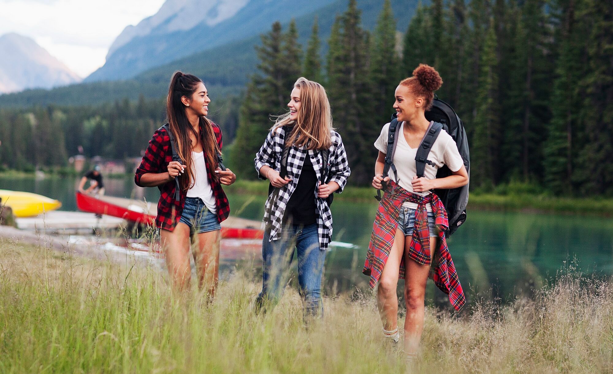 Three girls walk in a field in Banff National Park.
