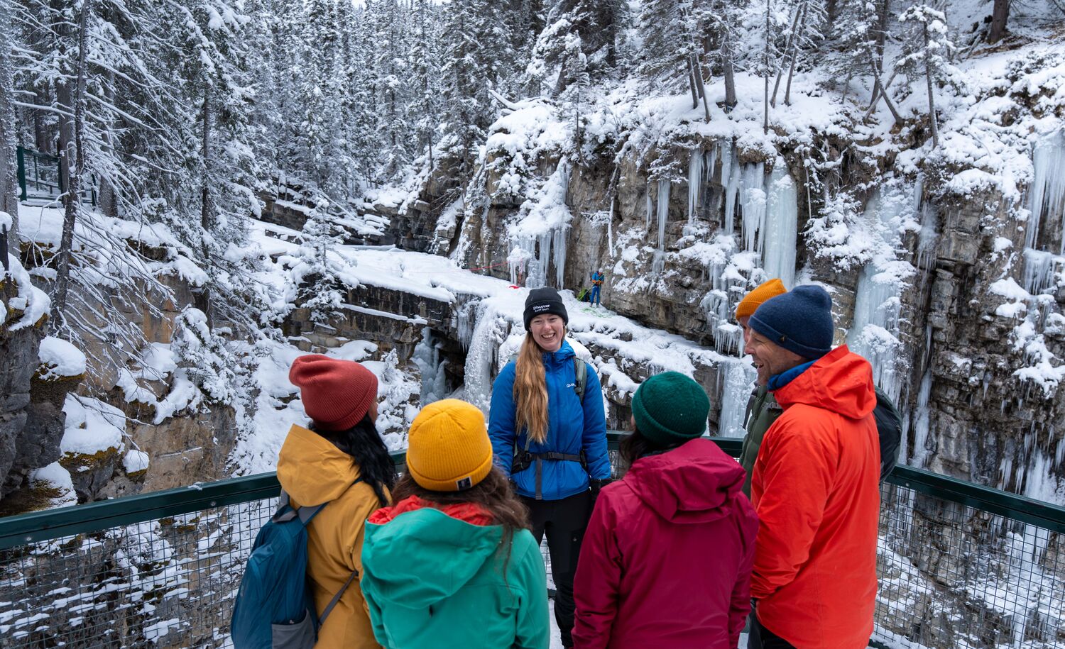 A group of people talk to a guide at Johnston Canyon in the winter at the upper falls in Banff National Park.