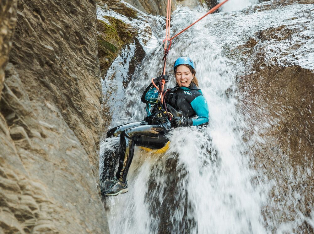 A women repeling down a canyon waterfall with Banff Canyoning, a popular thing to do in Banff in July