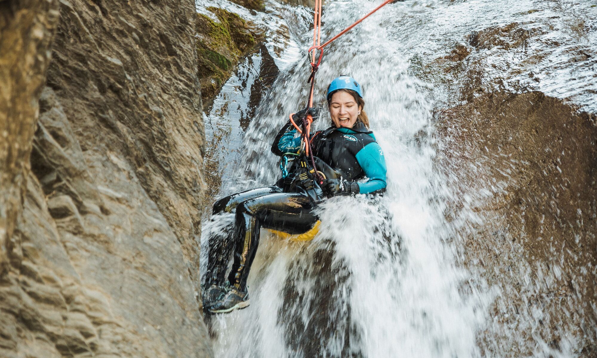 A women repeling down a canyon waterfall with Banff Canyoning, a popular thing to do in Banff in July