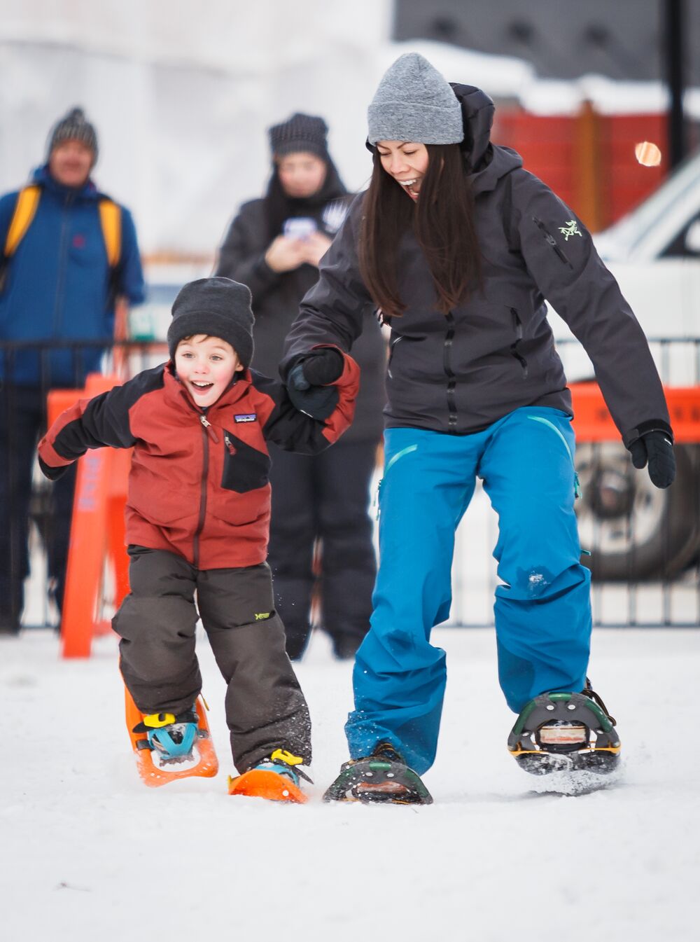 バンフで開催された SnowDays のお祝いで、スノーシューを履いてレースをする母と息子。