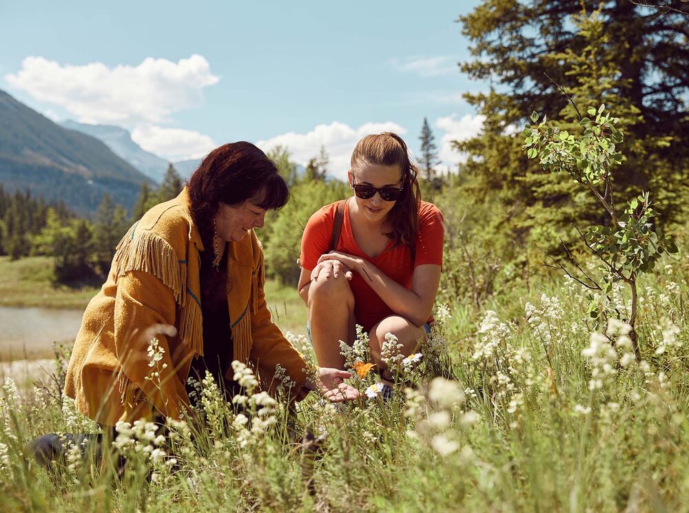 A woman and a guide look at plants during a Medicine Walk.