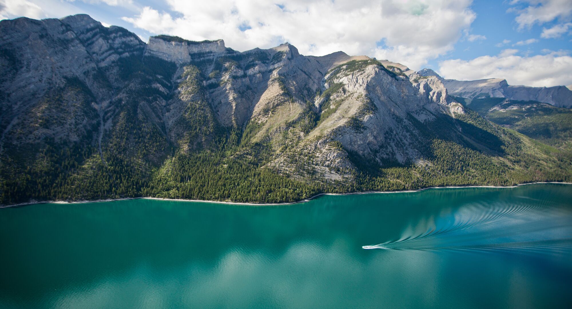 Aerial view of Lake Minnewanka with a boat cruising the waters