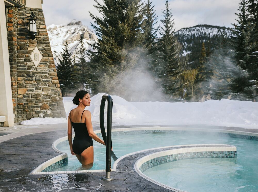 A woman enters an outdoor hot tub at the Fairmont Banff Springs Hotel.