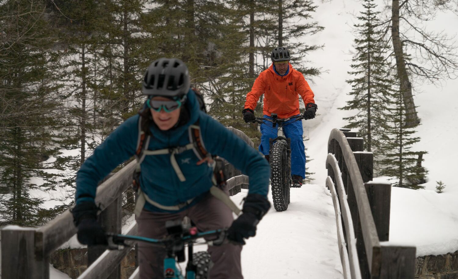 Two people bike across a bridge on the Spray River Trail in Banff National Park.