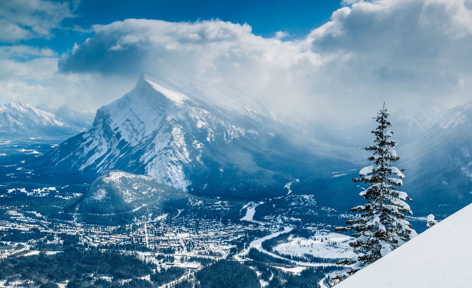 A snowy Moount Rundle with the Banff townsite below it as seen from Mt. Norquay in Banff National Park.