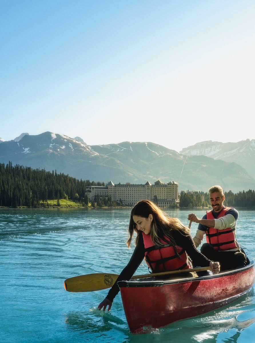 A couple paddling in a canoe on the turquoise waters of Lake Louise
