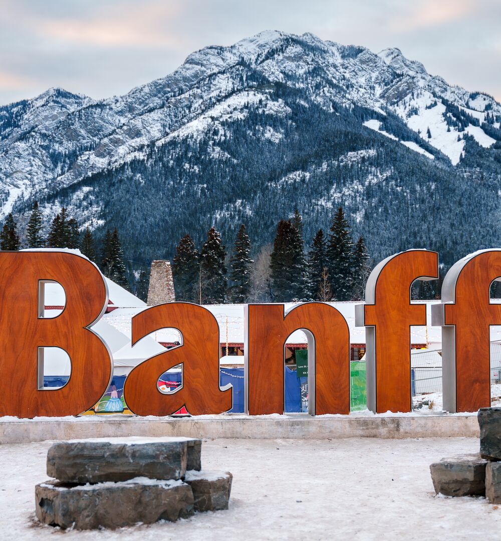 The iconic Banff sign with Cascade Mountain in the background and snow on the ground