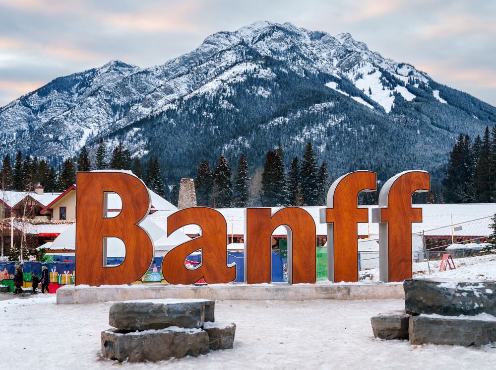 The iconic Banff sign with Cascade Mountain in the background and snow on the ground