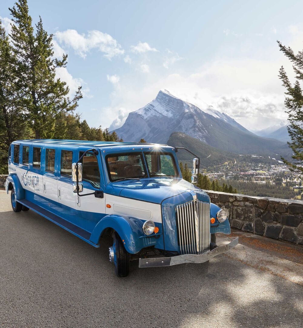 Person on a guided tour in the Banff area, taking a photo from the top of a open top bus