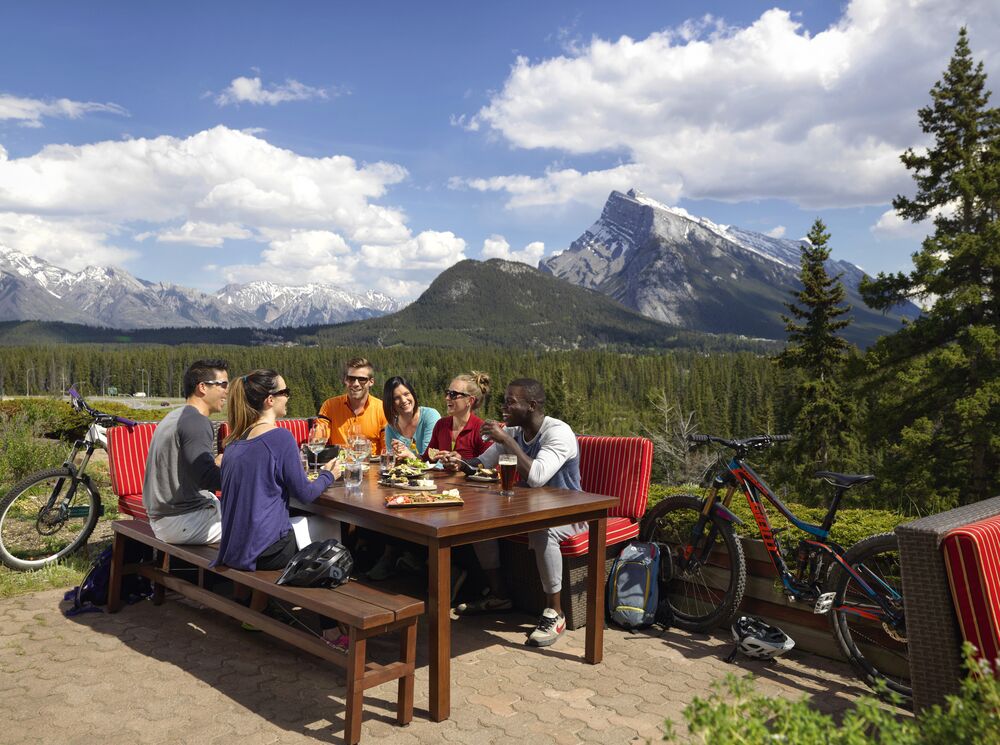 A group of people on an outdoor patio in Banff National Park, a popular thing to do in August
