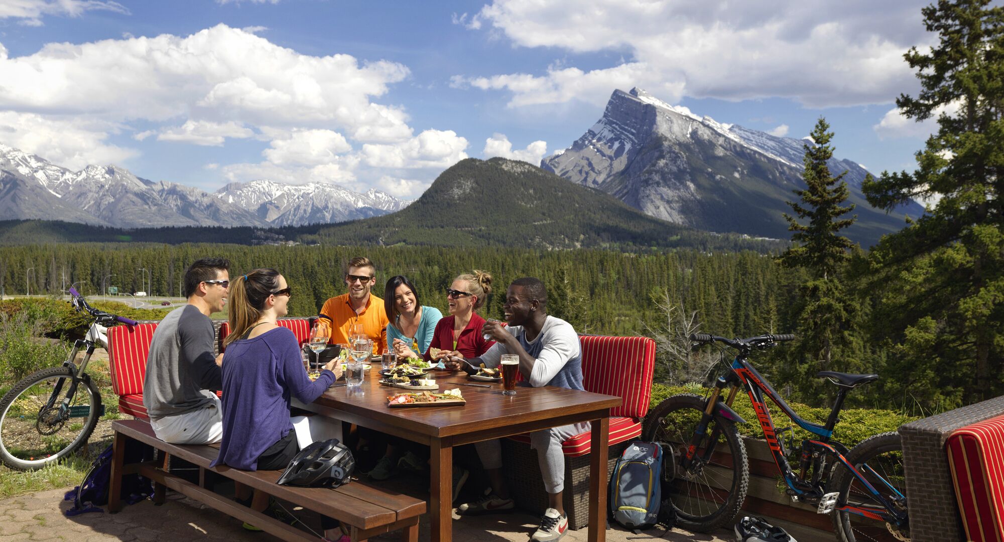 A group of friends enjoy a meal at the Juniper Bistro with a view of Mount Rundle out the window