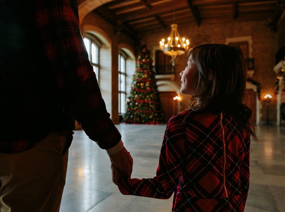 A little girl walking in front of a large Christmas tree at the Fairmont Banff Springs.