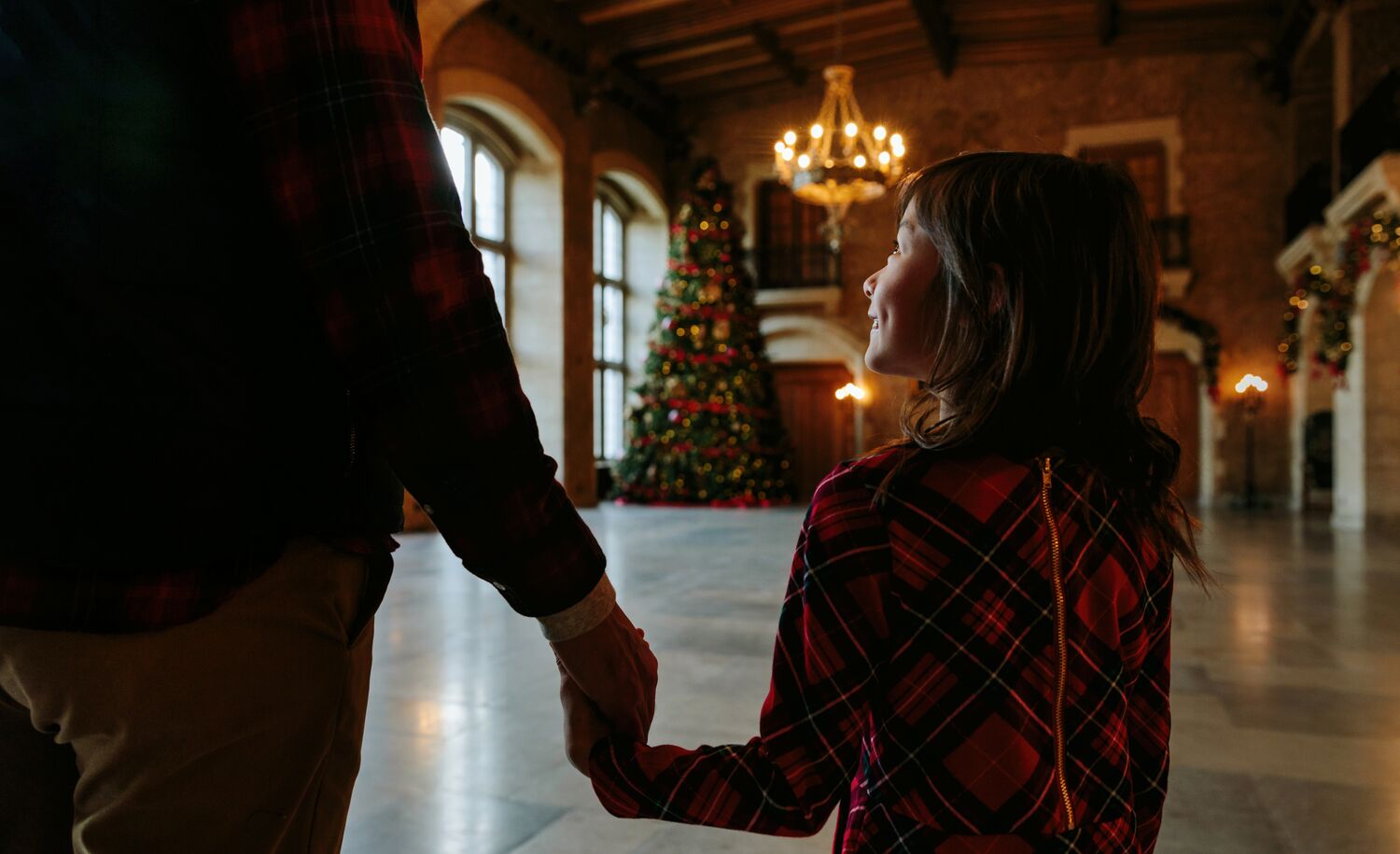 A little girl walking in front of a large Christmas tree at the Fairmont Banff Springs.