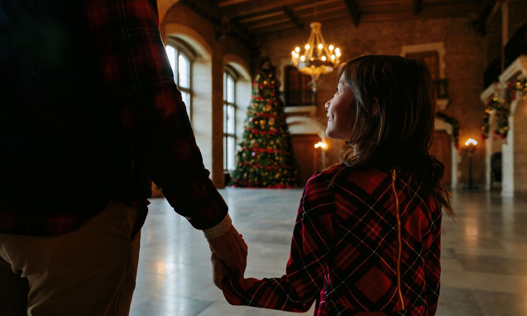 A little girl walking in front of a large Christmas tree at the Fairmont Banff Springs.