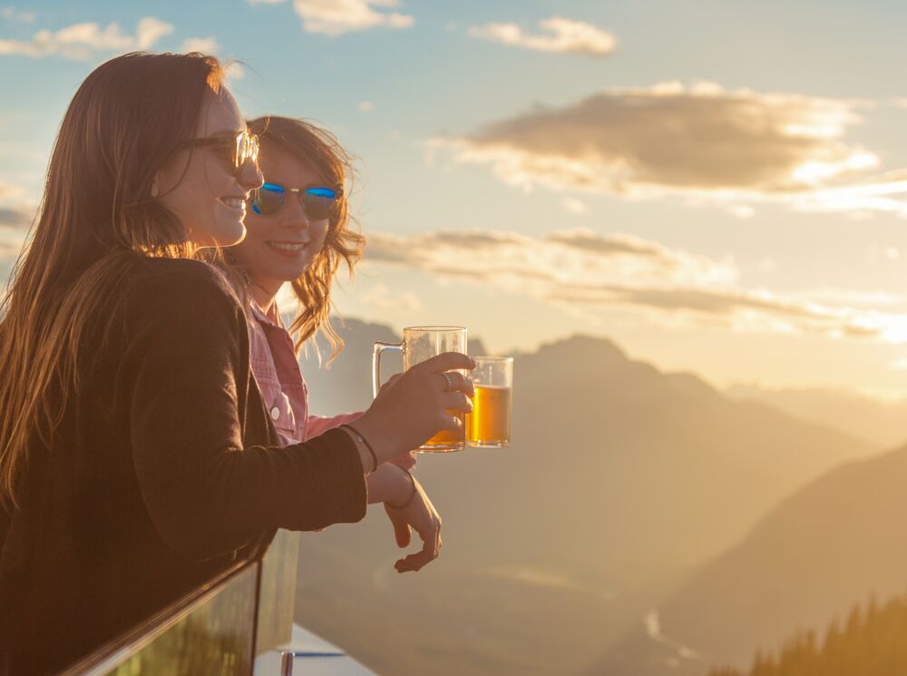 Two people having a dring on top of the Banff Gondola at the Sunset festival, a popular event in Banff in August